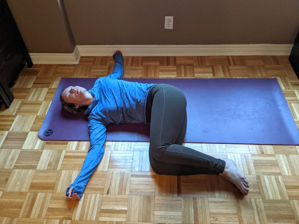 Mississauga physio showing a master revolved abdomen yoga pose, AKA supine twist stretch, for a restorative yoga blog