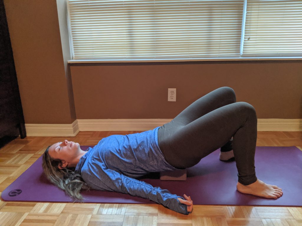 Oakville Physio showing a supported bridge post, using a yoga block, for a Restorative Yoga session at home
