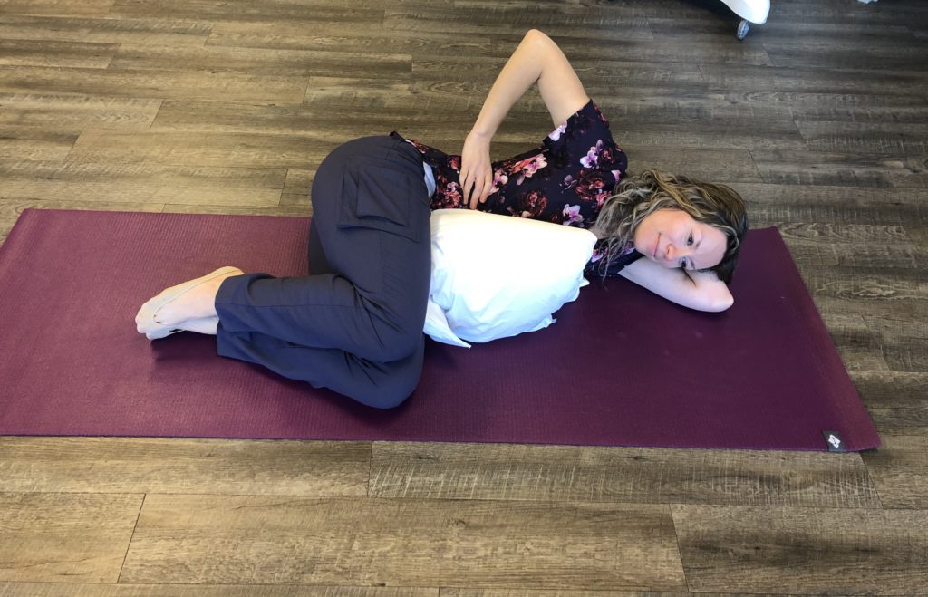 Picture of Oakville physio demonstrating a sidelying exercise in fetal position, to brace the abdominals and force the breath into the back